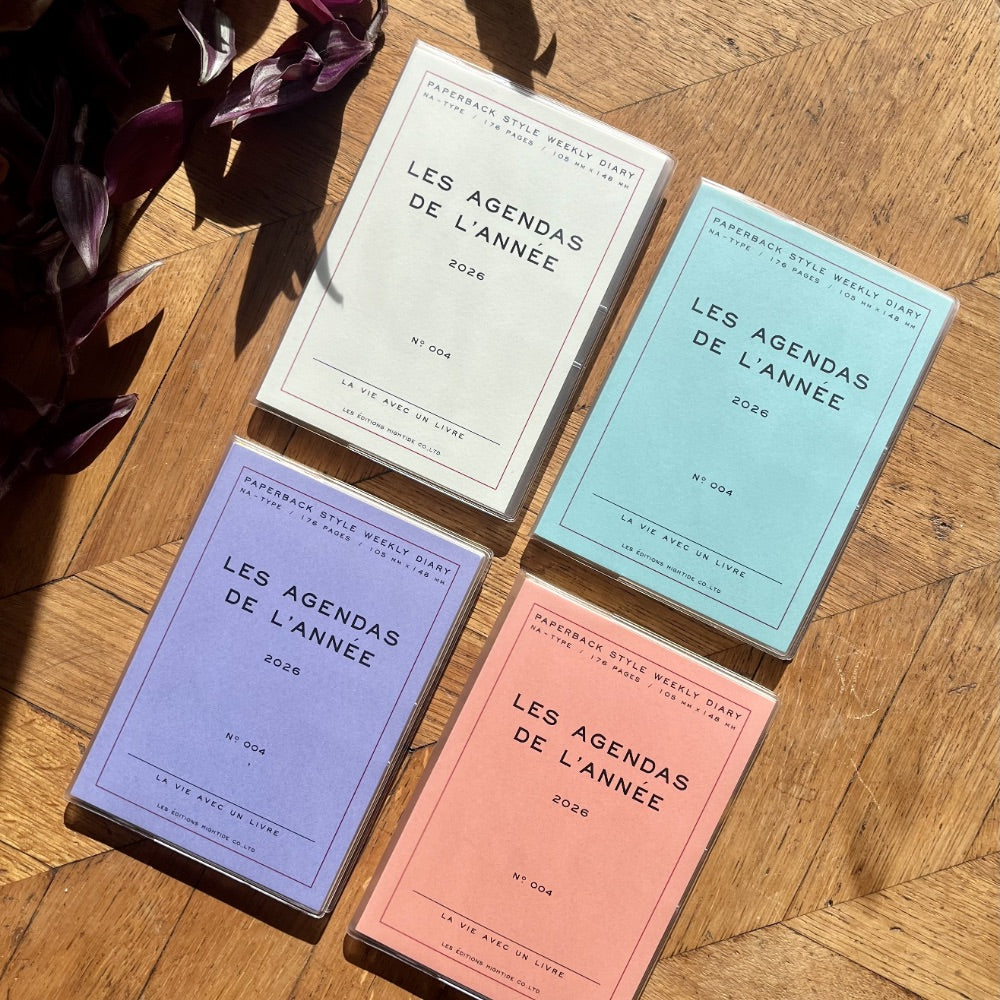 Four colorful diaries titled 'Les Agendas de l'Année' on a wooden surface.