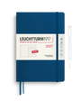 A Leuchtturm1917 2027 weekly planner and notebook in navy blue with a white paper band, shown alongside a white pen on a clean white background.