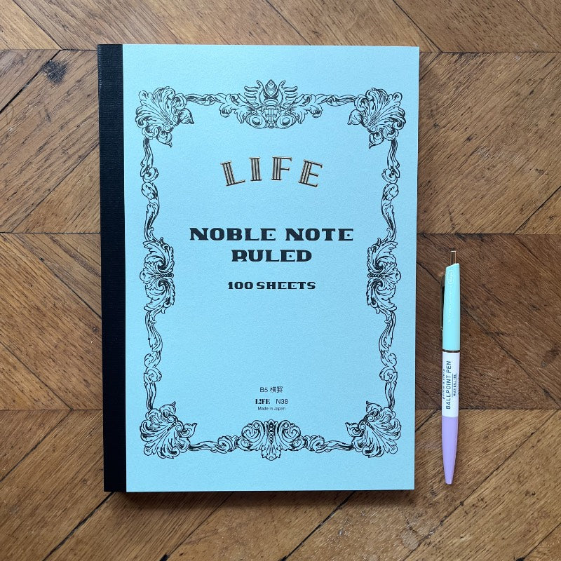 Blue notebook with decorative cover and a pen on a wooden surface