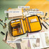 Yellow and brown organiser with pen board and stationery items on a green surface