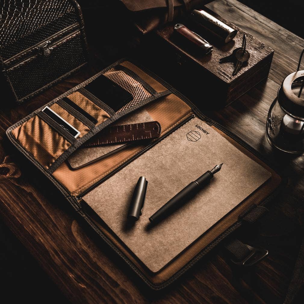 Brown leather travel set with stationery items on a wooden surface