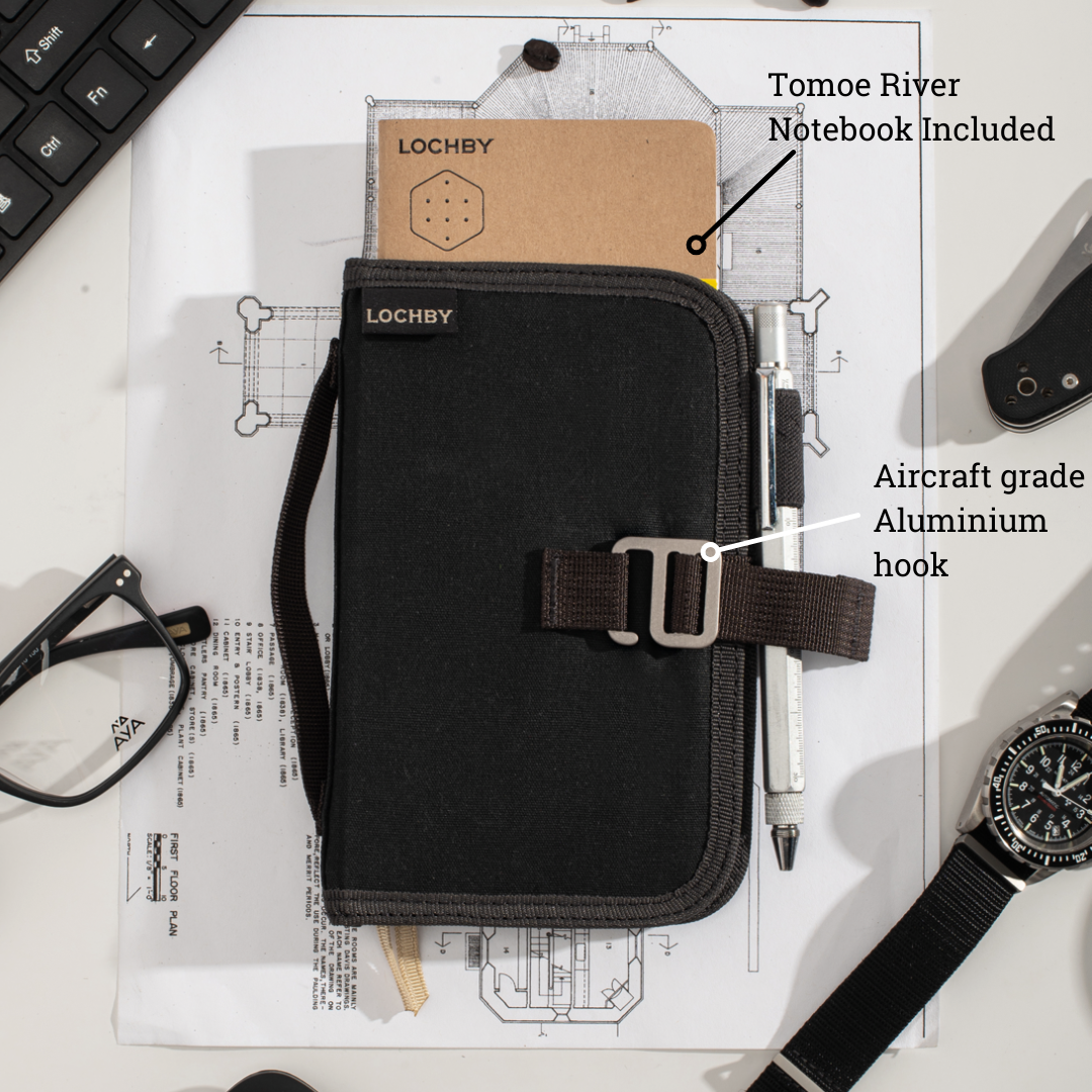 Black organizer with aircraft grade aluminium hook on a desk with notebook and glasses
