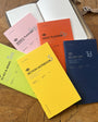 Collection of colorful planners and notebooks on a wooden surface