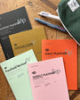 Collection of planners and a pencil case on a wooden surface