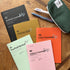 Collection of planners and a pencil case on a wooden surface