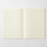 An open notebook with two blank cream-colored grid pages on a light gray background.
