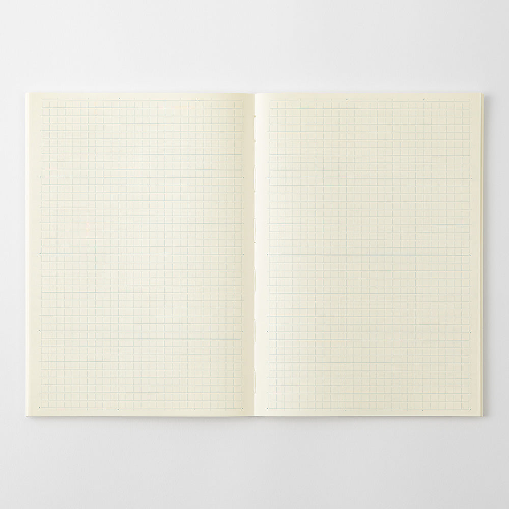 An open notebook with two blank cream-colored grid pages on a light gray background.