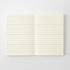 An open cream-colored lined notebook or journal, showing two blank pages with horizontal ruled lines, set against a clean white background.