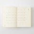 An open planner or journal showing two blank calendar pages with a light cream background and thin gray grid lines, photographed on a clean white background.