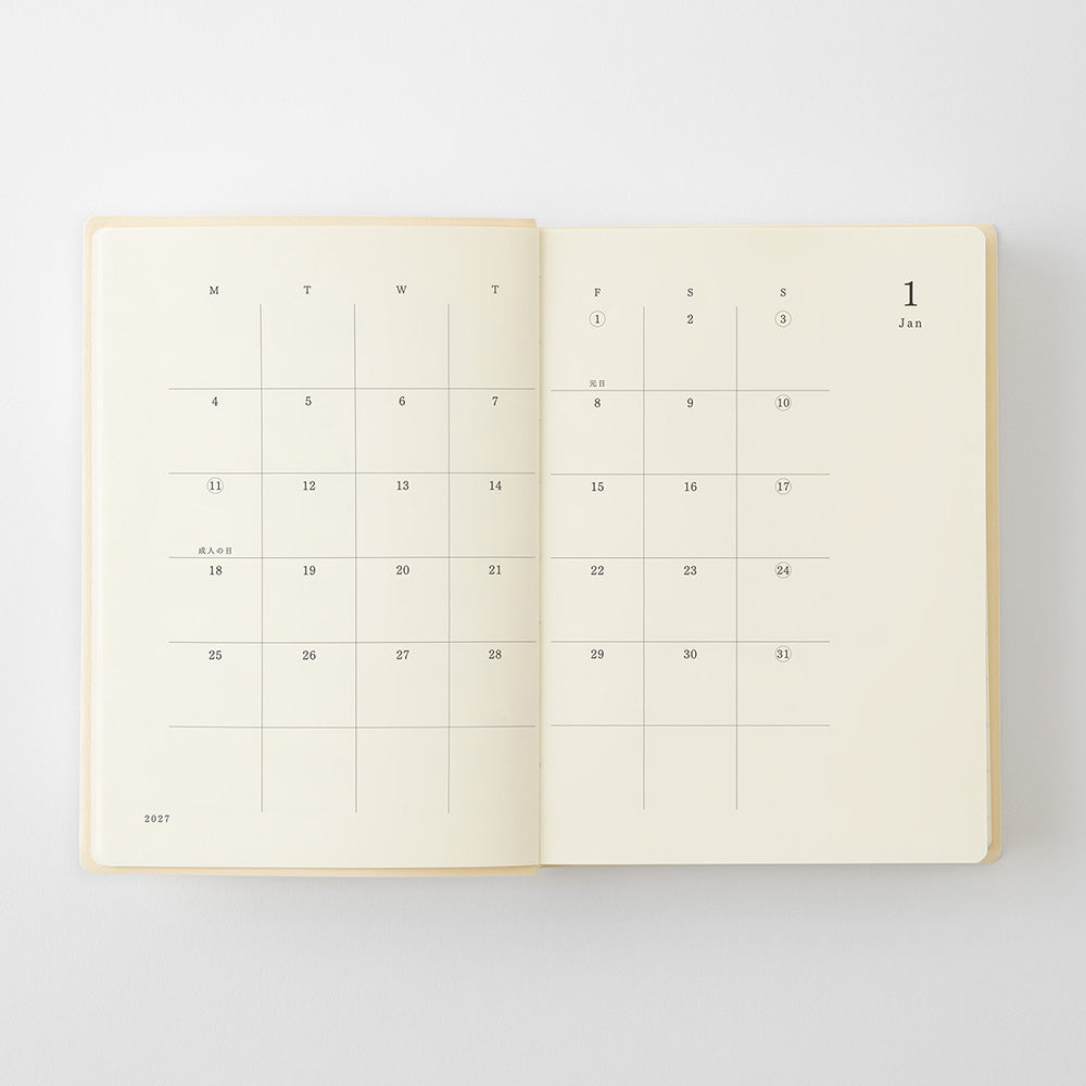 An open planner or journal showing two blank calendar pages with a light cream background and thin gray grid lines, photographed on a clean white background.