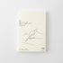 A cream-colored notebook or diary with minimalist black line art showing hands writing, set against a clean white background. The cover features Japanese text and the brand logo 'MD PRODUCT'.