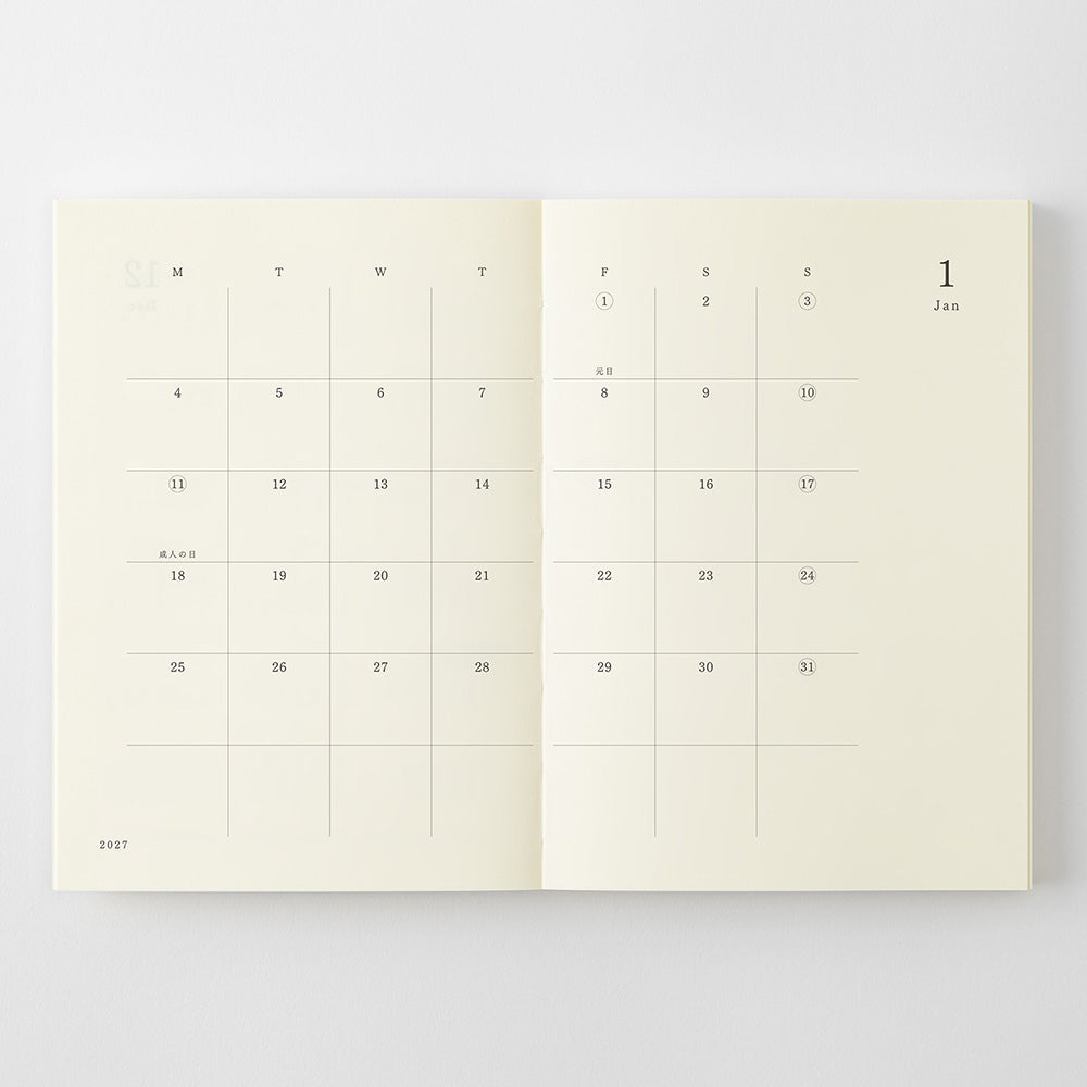 An open planner or notebook showing two cream-colored calendar pages with minimalist black grid lines and day labels, photographed against a light gray background.