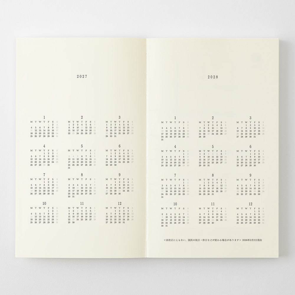 An open book or planner spread showing two cream-colored pages with printed calendar grids for 2027 and 2028, photographed against a light gray background.