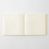 An open cream-colored notebook with lined pages, photographed flat against a light gray background.