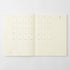 An open cream-colored planner or notebook showing minimalist monthly calendar pages with dates and weekday grids on a light gray background.