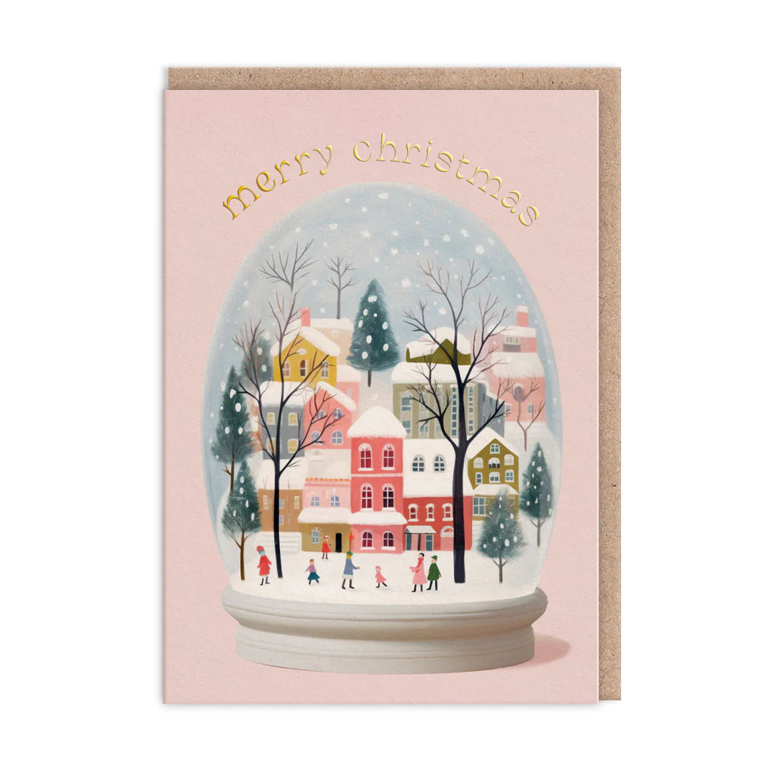 Christmas card with a snow globe design featuring a village scene and 'Merry Christmas' text on a pink background.