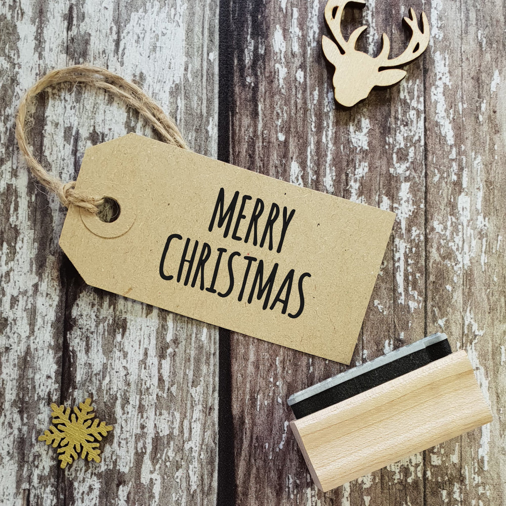 Kraft paper tag with 'Merry Christmas' text on a wooden surface with decorative elements.
