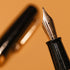 Close-up of a fountain pen with detailed nib on a warm brown background