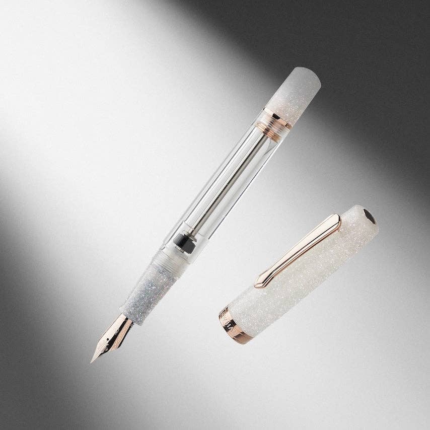 Fountain pen with glittery white cap and rose gold accents on a gradient gray background