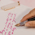Handwritten text on paper with a pen and clip in the background