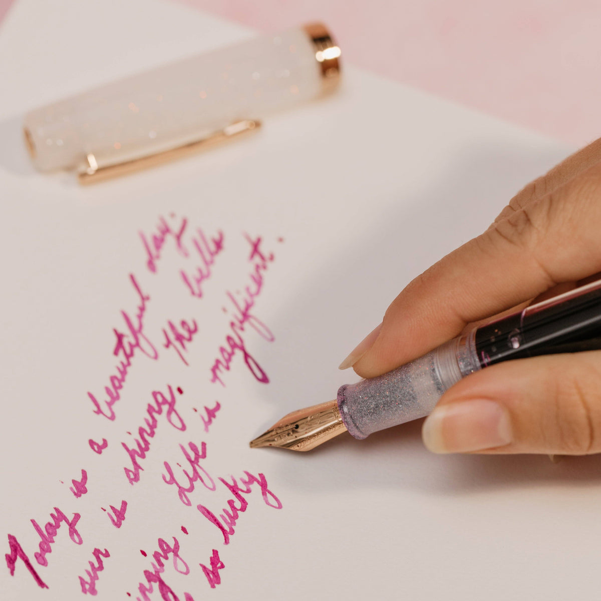 Handwritten text on paper with a pen and clip in the background