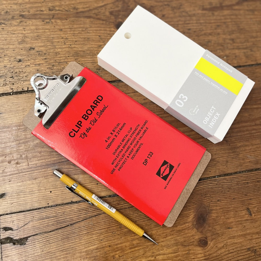 Red clipboard with a yellow pen on a wooden surface
