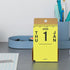 Yellow desk calendar for 2026 on a gray surface with office supplies in the background.