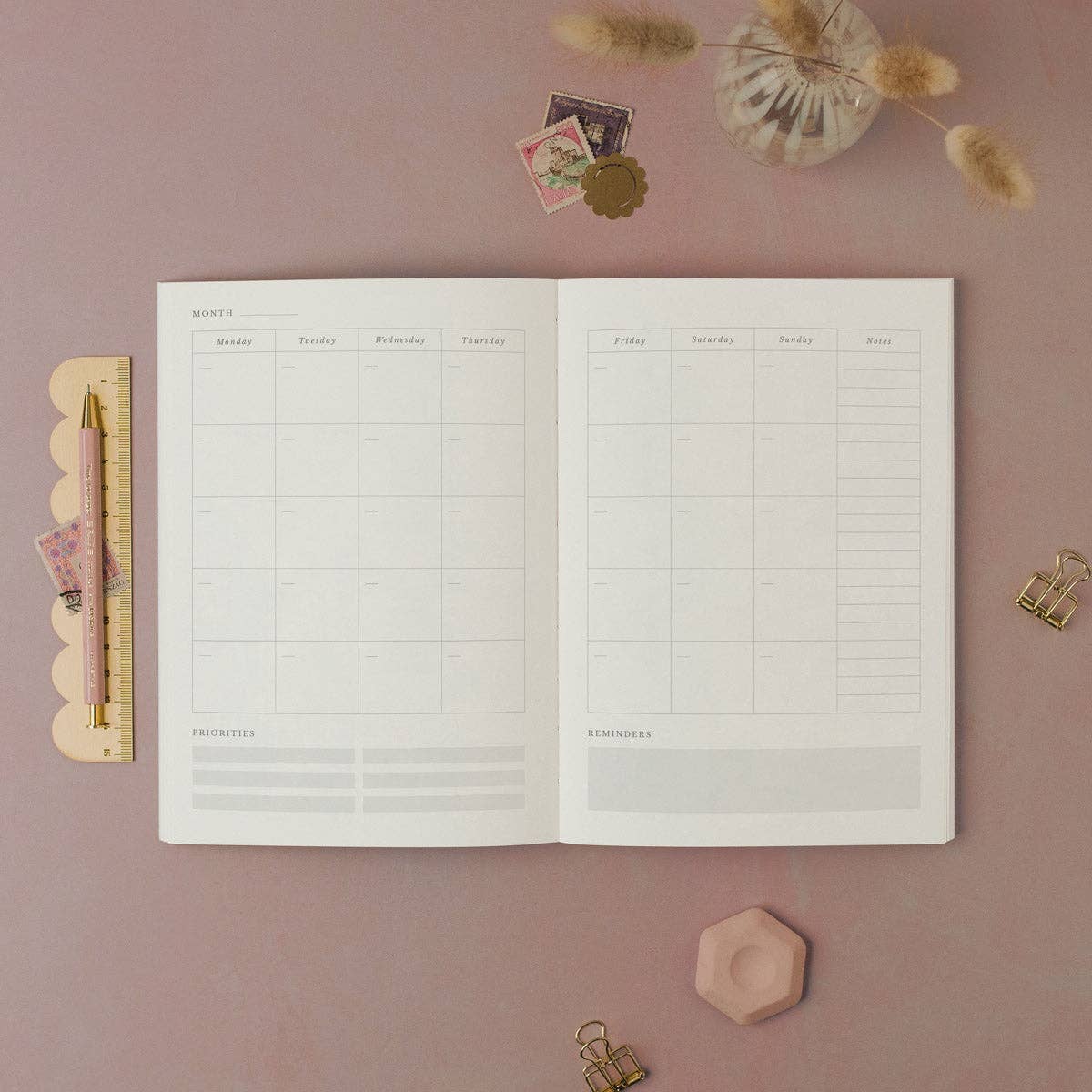 Open planner on a pink surface with decorative items