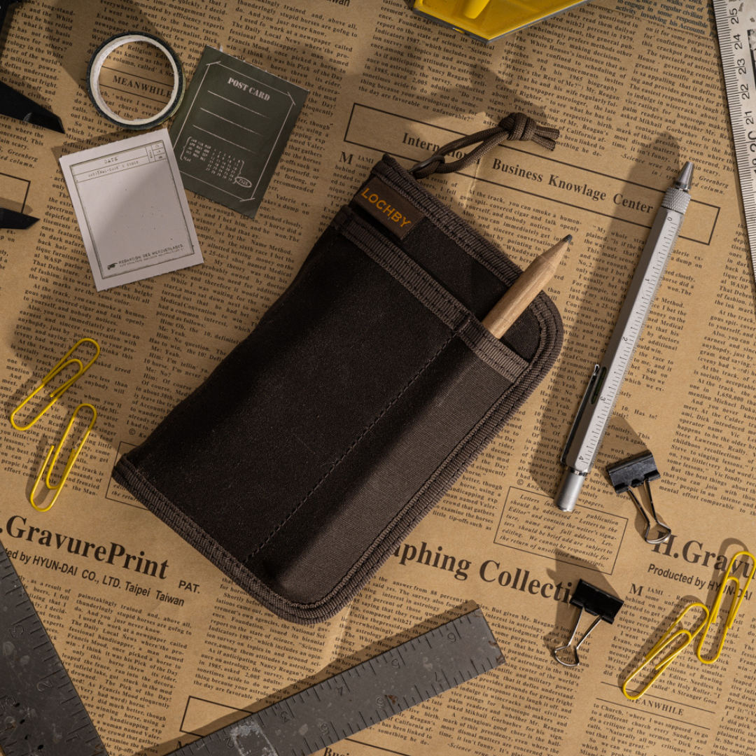 Black pouch on a newspaper background with stationery items