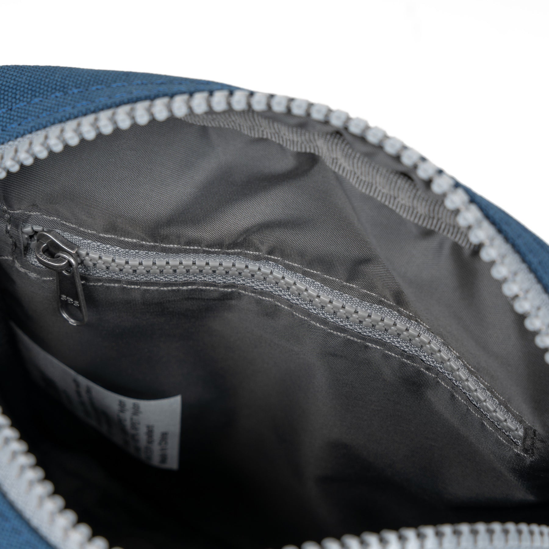 Close-up of a blue and gray bag with a zipper, showing the interior.