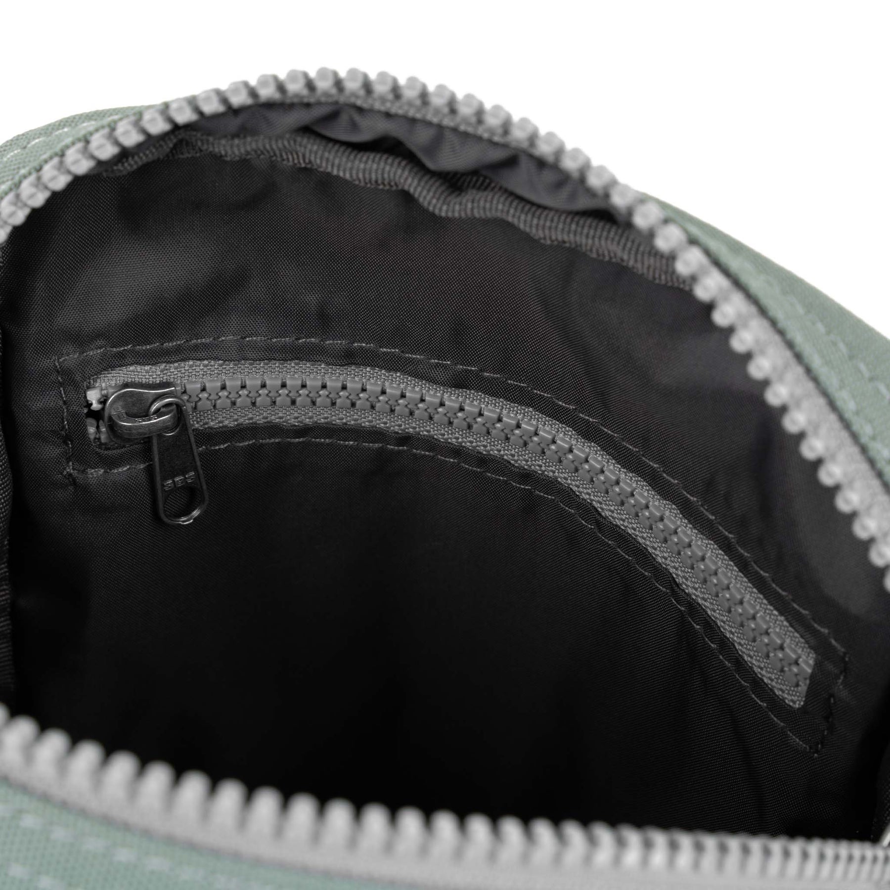 Close-up of a zipper on a pewter and black bag with a white border.