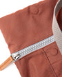 Close-up of a brown fabric bag with a silver zipper on a white background