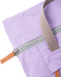 Close-up of a purple bag with a zipper and brown handle on a white background