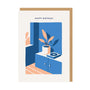 Greeting card with a blue cabinet, plant, and record player illustration, and 'Happy Birthday' text.