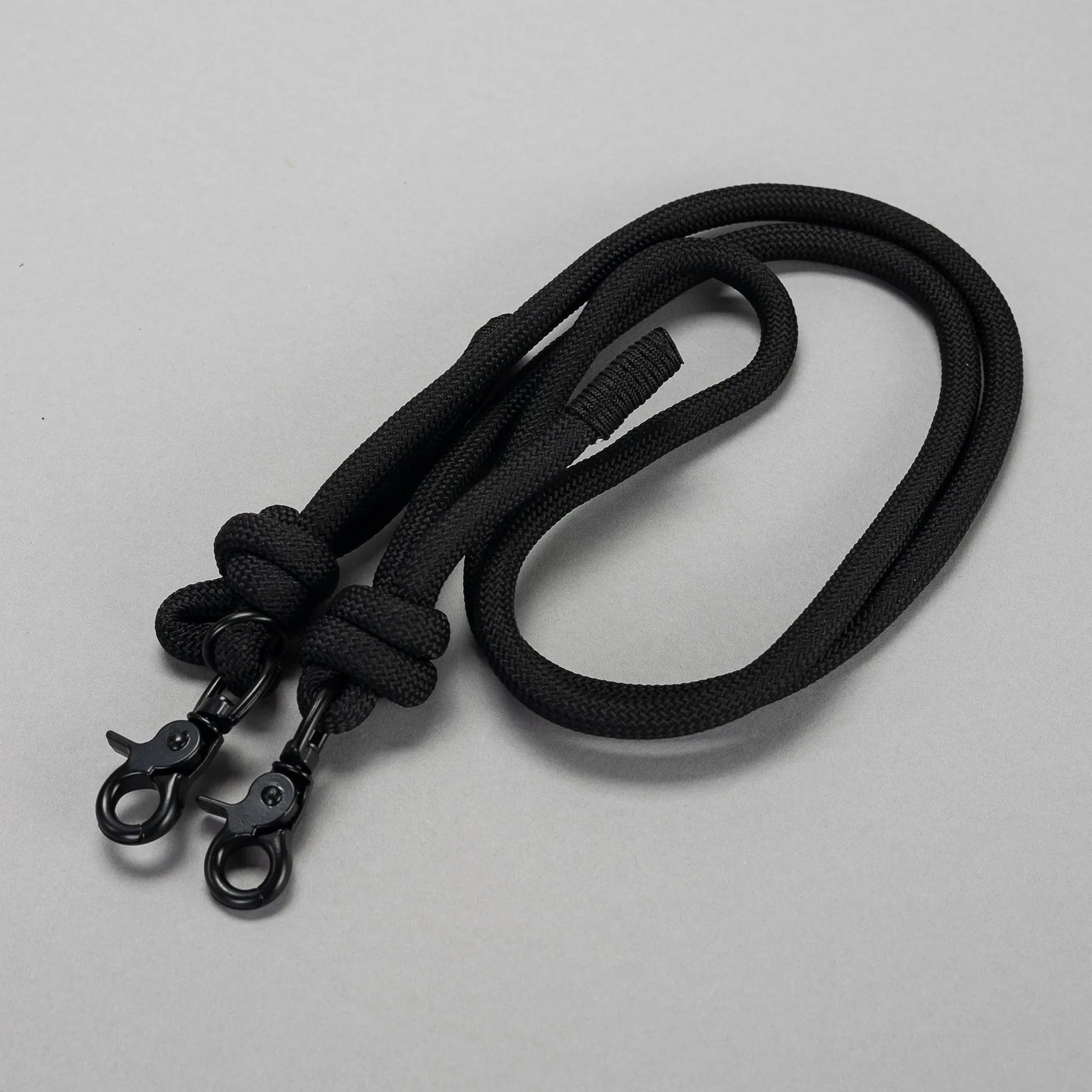 Black lanyard with two carabiners on a light gray background