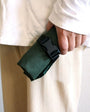 Person holding a green belt with a black buckle against a neutral background