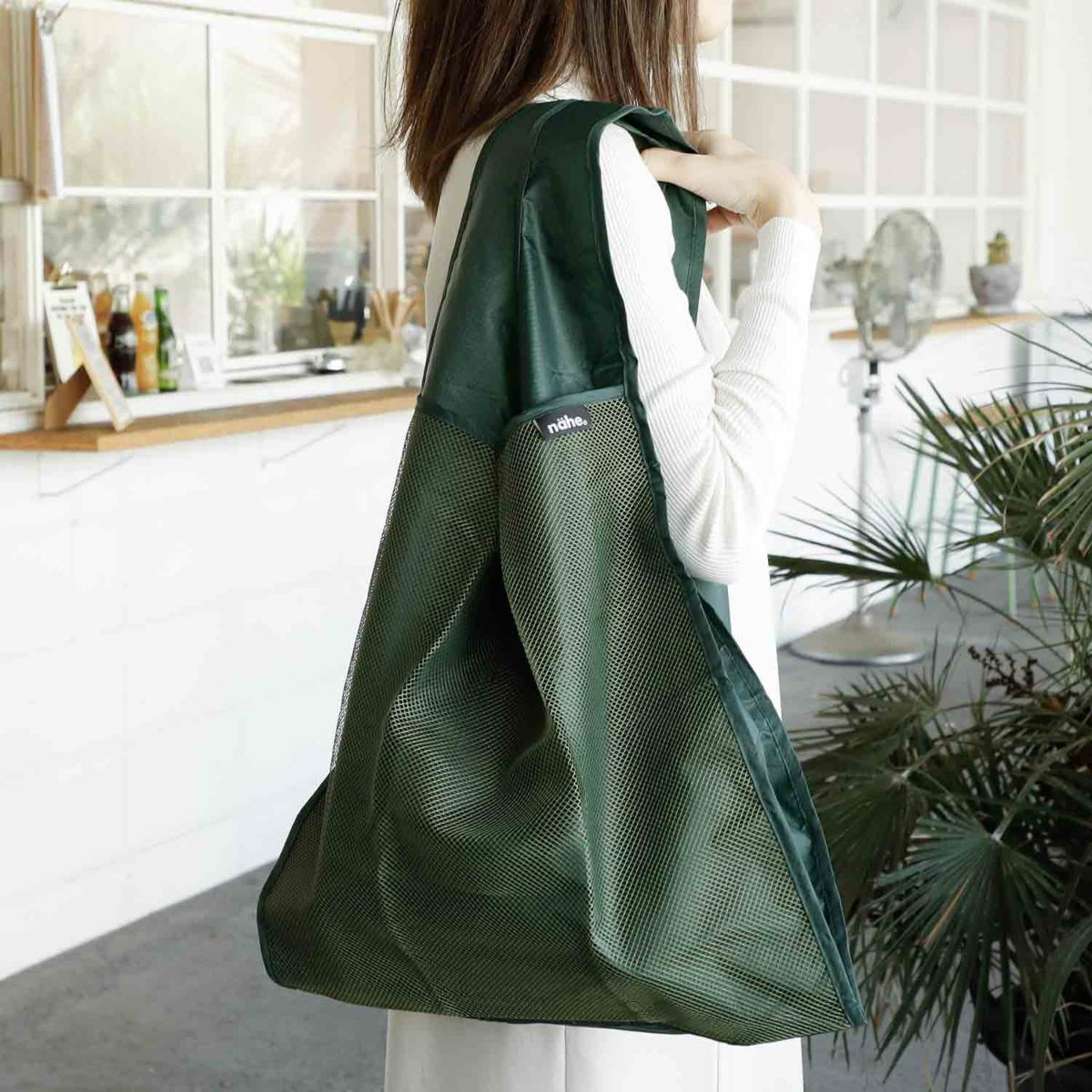 Person holding a green reusable bag in a kitchen setting
