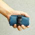Hand holding a blue textured pouch with a black buckle against a neutral background