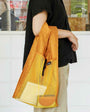 Person holding a yellow mesh bag with a blurred indoor background