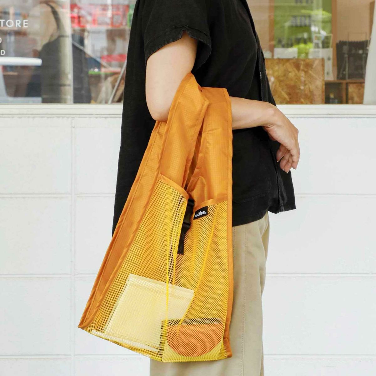 Person holding a yellow mesh bag with a blurred indoor background