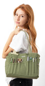 Woman holding a green bag with various compartments on a white background