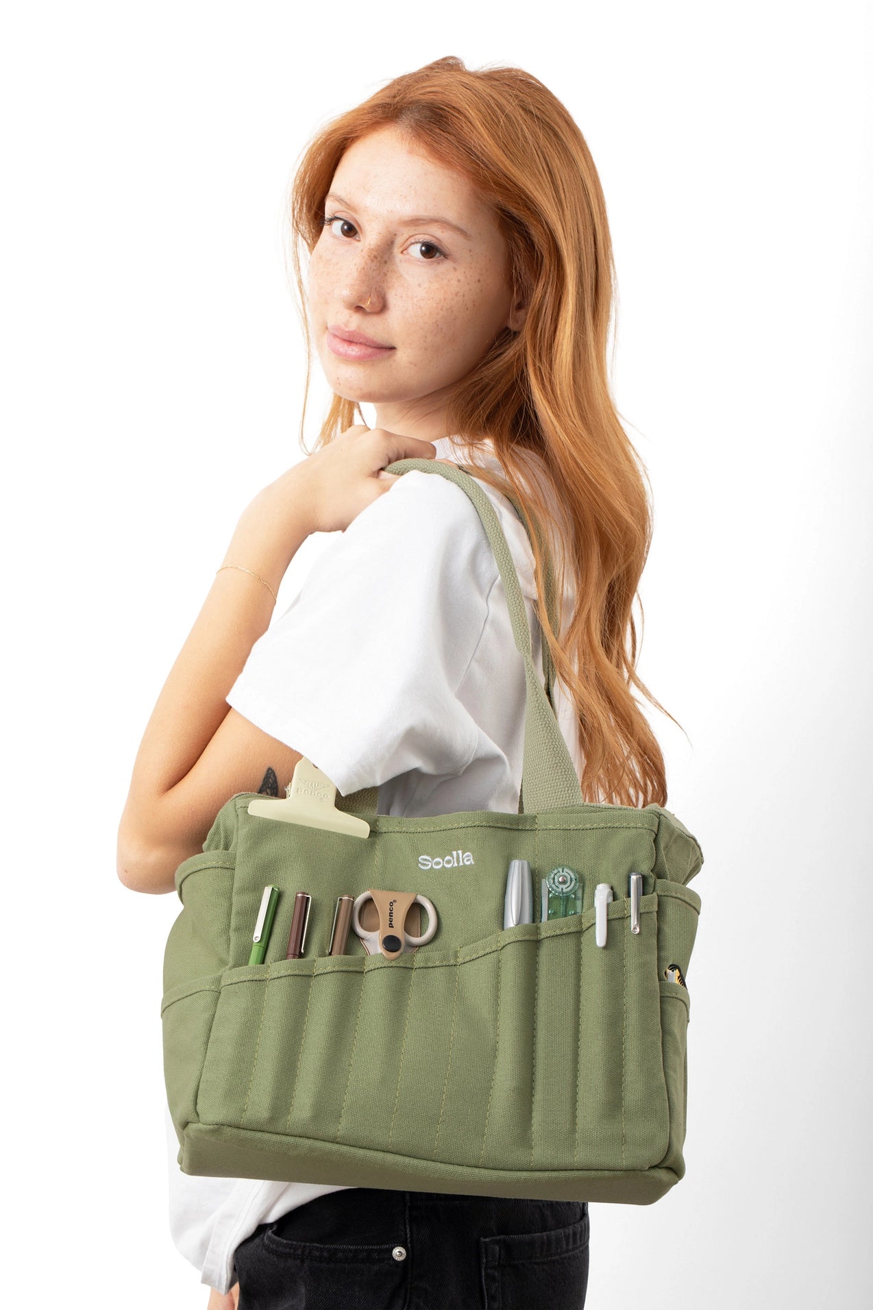 Woman holding a green bag with various compartments on a white background