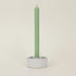 Green candle in a gray holder on a beige background