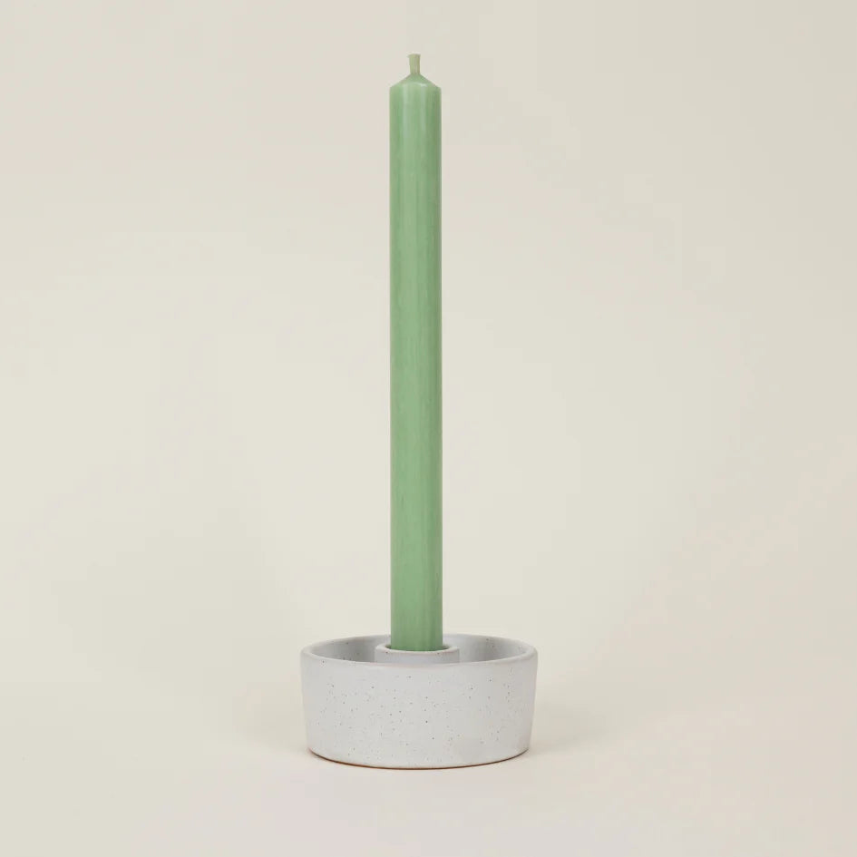 Green candle in a gray holder on a beige background