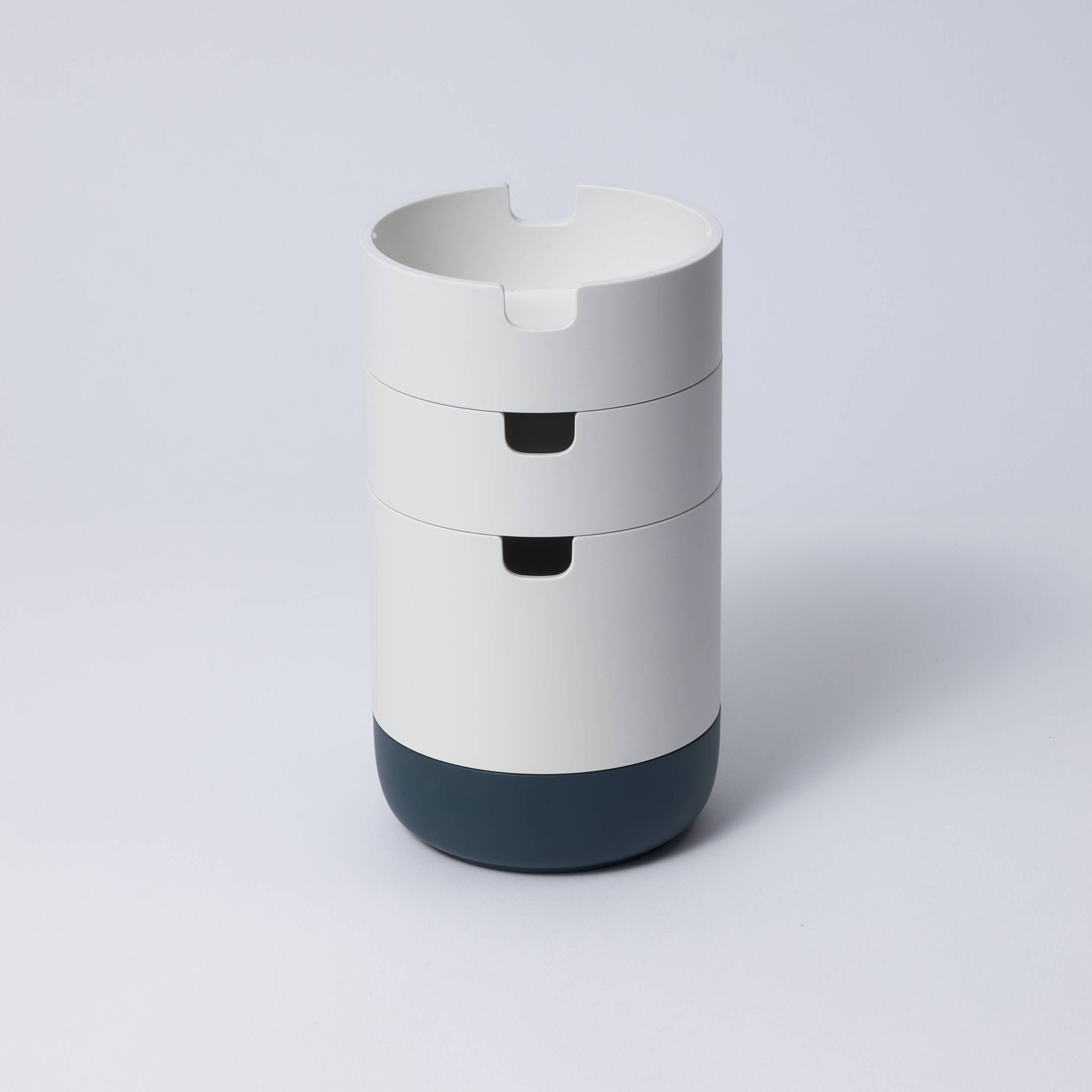 A collection of stackable organizer cases in various colors with a matte porcelain-like finish, designed to hold stationery items.