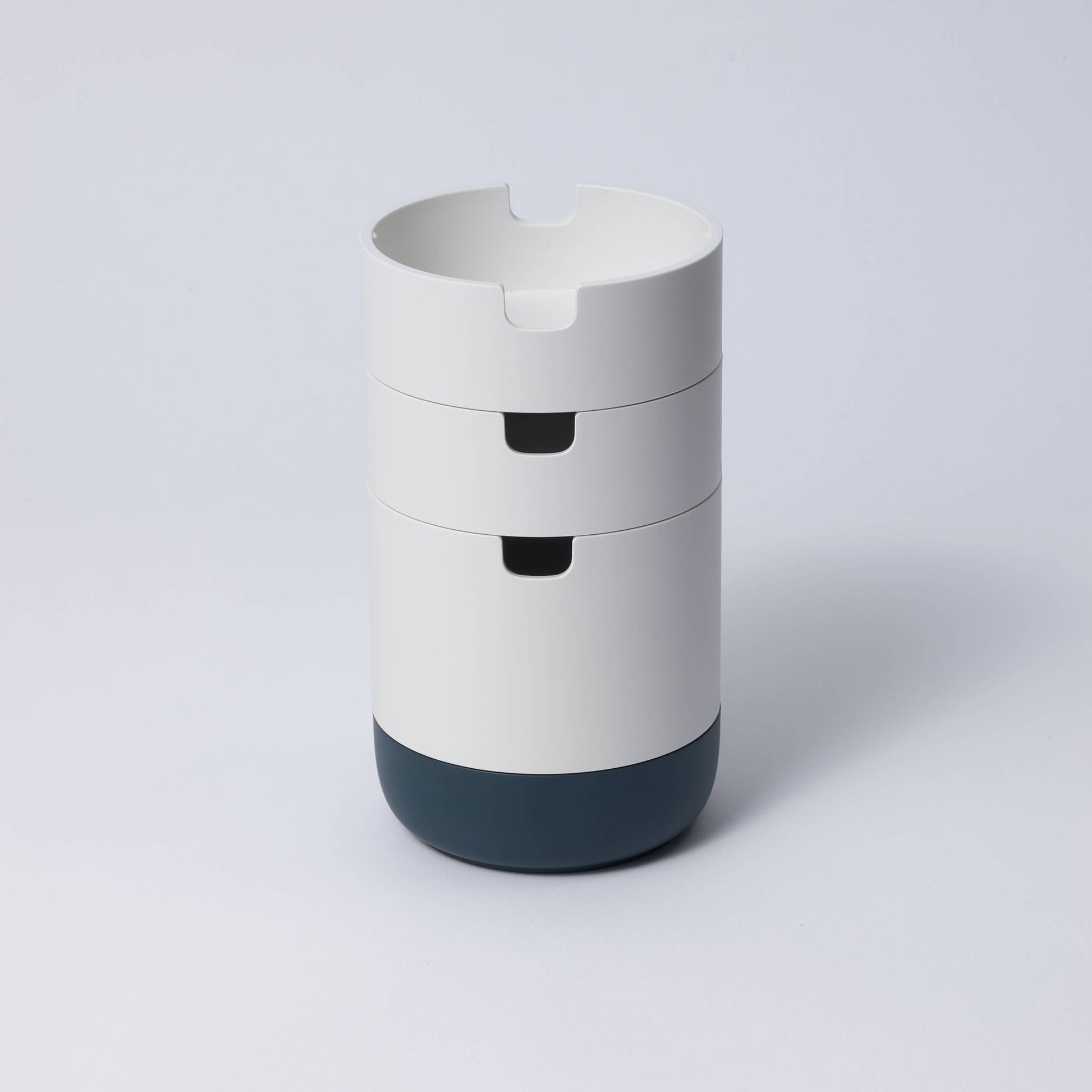 A collection of stackable organizer cases in various colors with a matte porcelain-like finish, designed to hold stationery items.