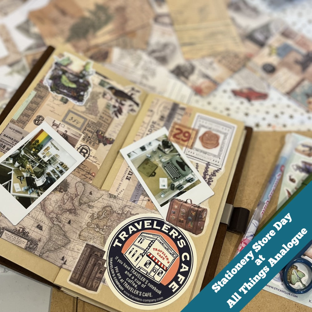 Decorative notebook with travel-themed stickers and a visible 'Traveler's Company' logo, surrounded by other stationery items.