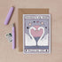 Wedding card with swans and 'Congrats on your wedding day' text, next to a pen and envelope on a beige background