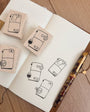 Rubber stamps with design on a notebook with a pen on a wooden surface