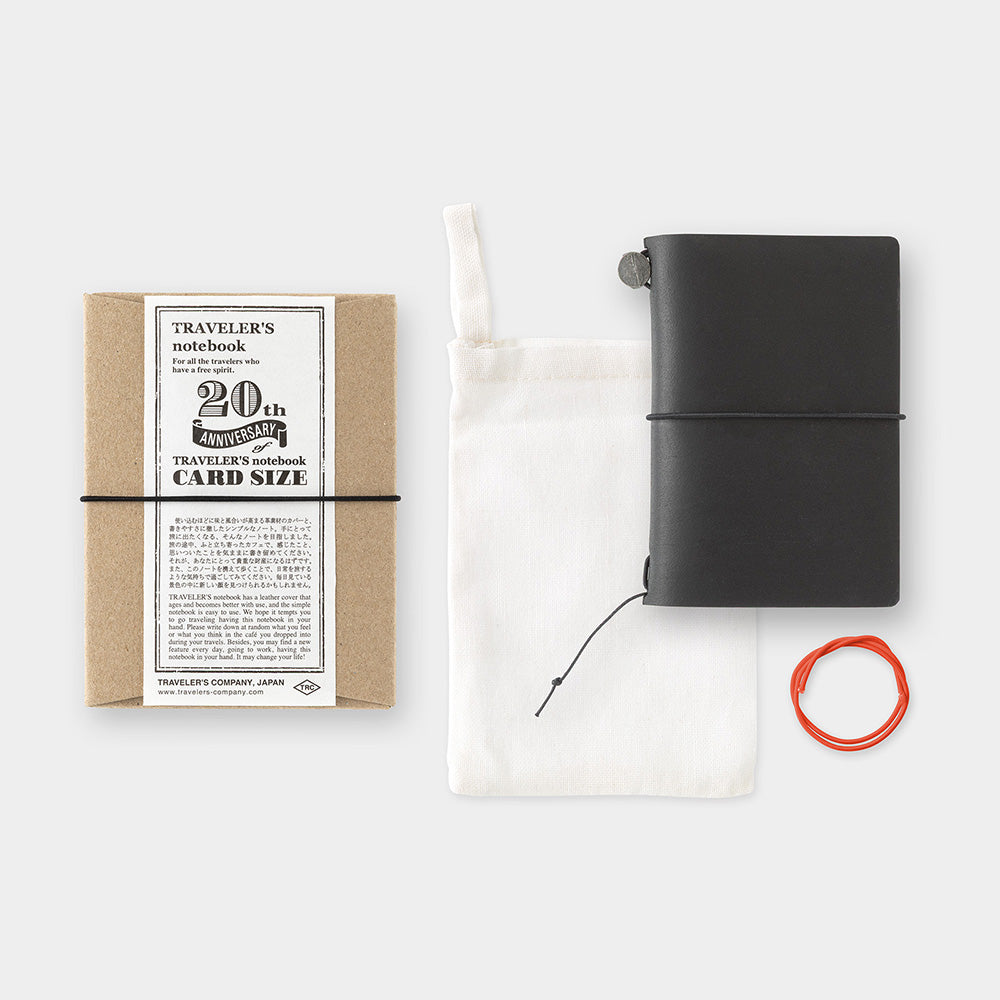 Black travel notebook with packaging and accessories on a white background